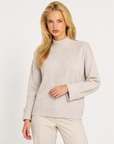 Maglia donna collo alto beige con bottoni sui polsini indossata da Polly 7, vista a tre quarti