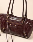 Dettaglio borsa in ecopelle bordeaux con zip e finiture color ottone