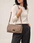 Borsa a tracolla in vera pelle scamosciata con borchie taupe indossata a spalla