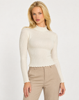 Maglia donna bianco a costine con collo alto e punti luce indossata da Polly 7, vista a tre quarti