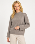 Maglia donna collo alto taupe con bottoni sui polsini indossata da Polly 7, vista a tre quarti
