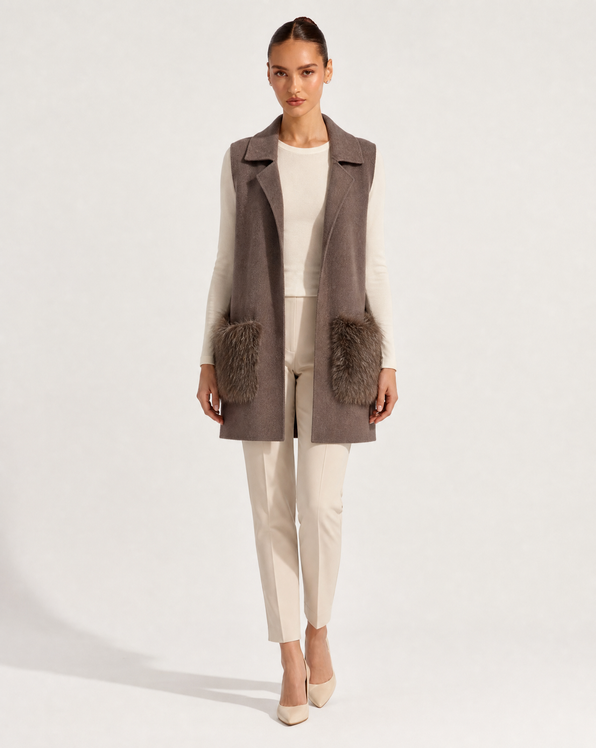 Gilet lungo con tasche in ecopelliccia marrone indossato da modella, vista frontale