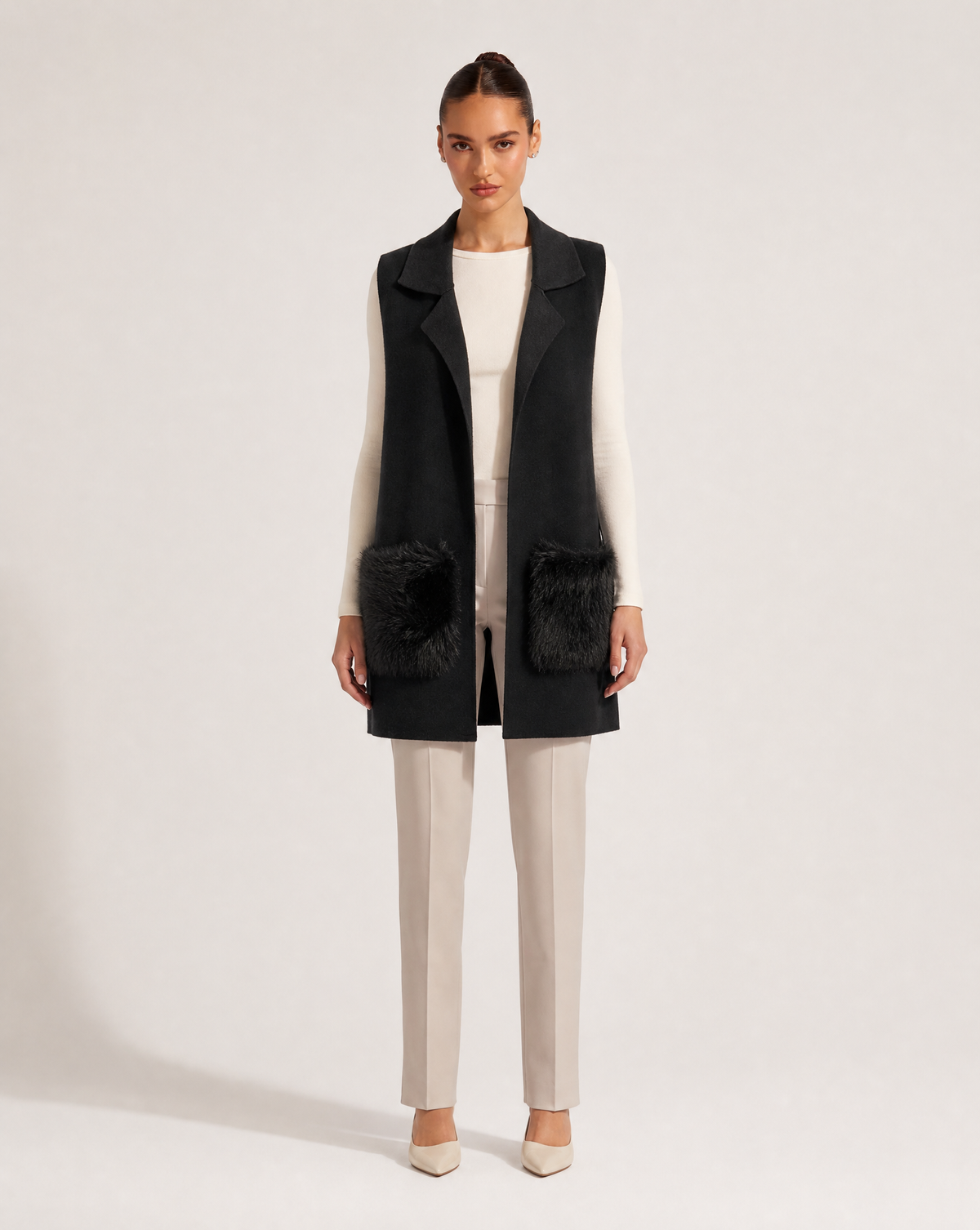 Gilet lungo con tasche in ecopelliccia nero indossato da modella, vista frontale