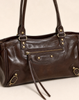 Dettaglio borsa in ecopelle marrone con zip e finiture color ottone