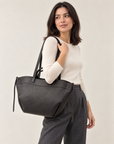 Borsa shopper nera in vera pelle con doppi manici indossata a spalla
