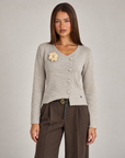 Cardigan donna beige con fiore e bottoni asimmetrici, indossato da Polly 4 con pantaloni spigati – vista frontale