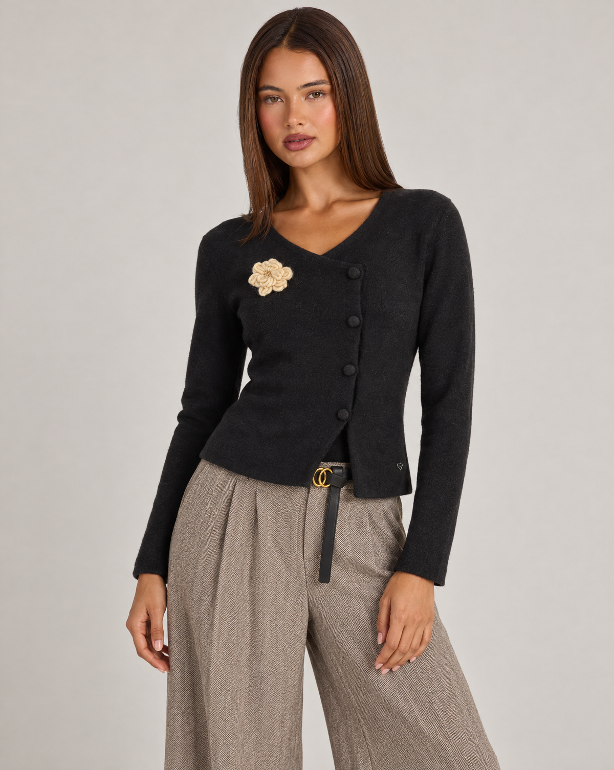 Cardigan donna nero con fiore e bottoni asimmetrici, indossato da Polly 4 con pantaloni spigati – vista tre quarti