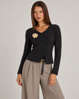 Cardigan donna nero con fiore e bottoni asimmetrici, indossato da Polly 4 con pantaloni spigati – vista tre quarti