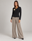 Polly 4 a corpo intero con cardigan donna nero con fiore e abbottonatura asimmetrica, abbinato ai pantaloni a palazzo spigati color fango