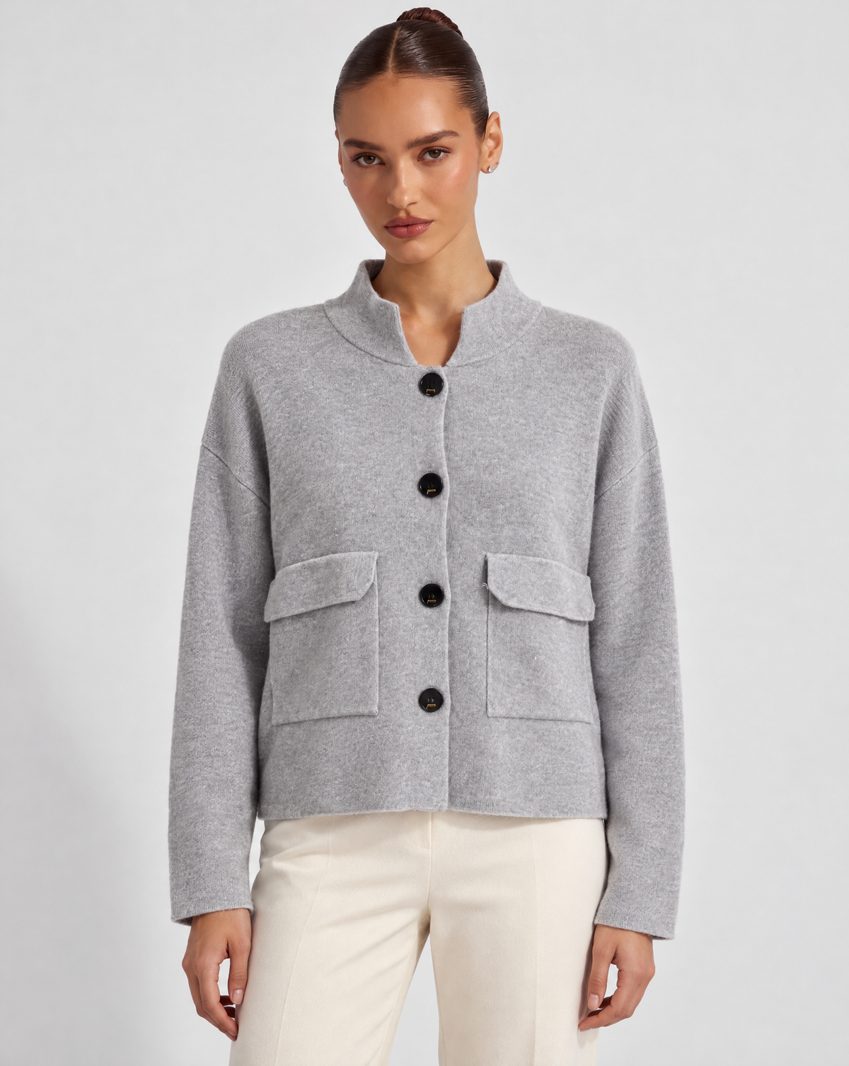 Cardigan donna corto grigio con collo alto, bottoni e tasche, indossato da Polly 6 – frontale
