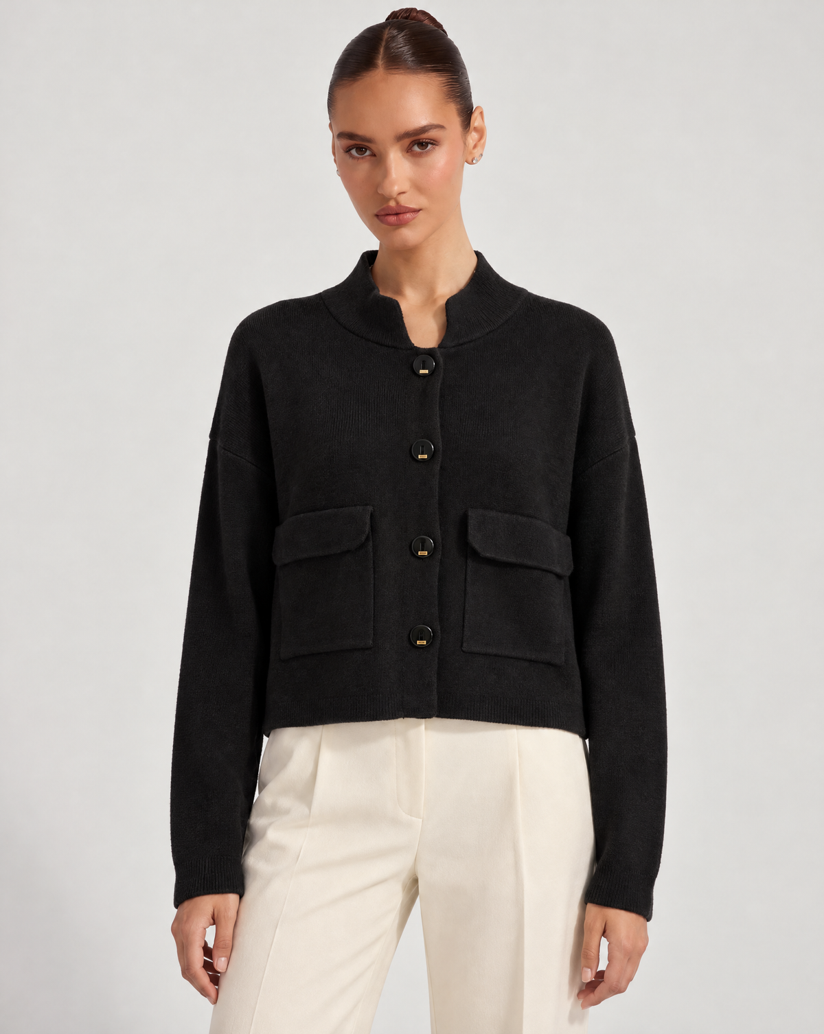 Cardigan donna corto nero con collo alto, bottoni e tasche, indossato da Polly 6 – frontale