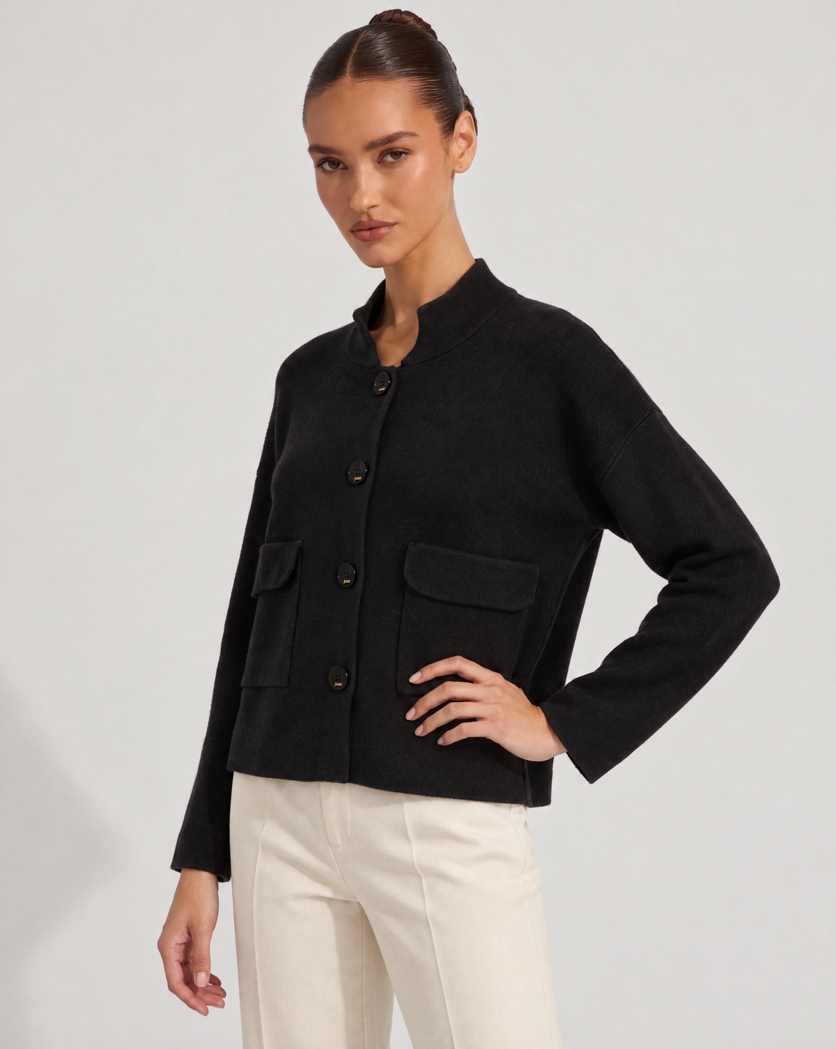 Cardigan donna corto nero con collo alto, bottoni e tasche, indossato da Polly 6 – tre-quarti