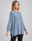 Maglia lunga con tasche frontali azzurro indossata da Polly 5, vista tre quarti